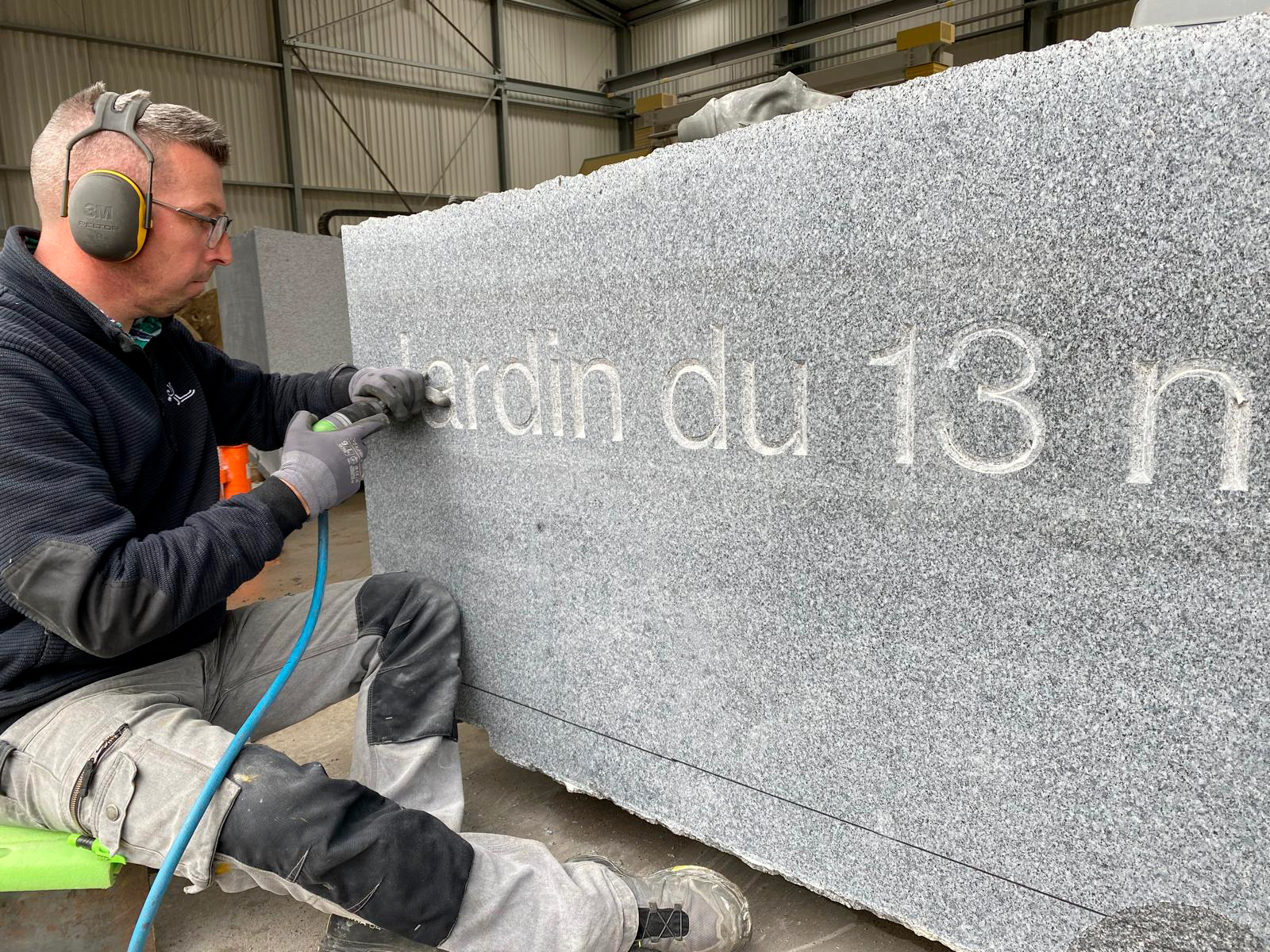 Artisan graveur réalisant des inscriptions mémorielles sur pierre au jardin mémoriel des attentats de Paris
