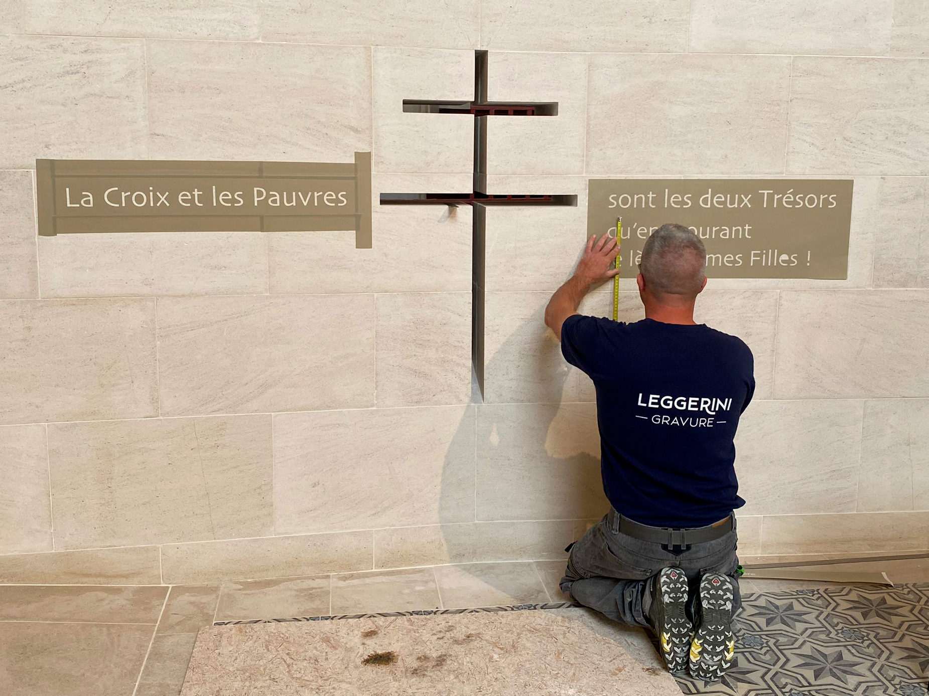 Artisan graveur réalisant une gravure patrimoniale sur pierre pour le sanctuaire de la Vraie Croix d’Anjou